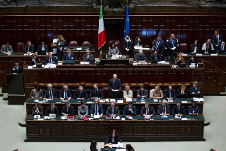 Prime Minister Enrico Letta, standing at center surrounded by his Cabinet, delivers his speech during a vote of confidence to confirm the government, in the lower house of Parliament, in Rome, Monday, April 29, 2013.