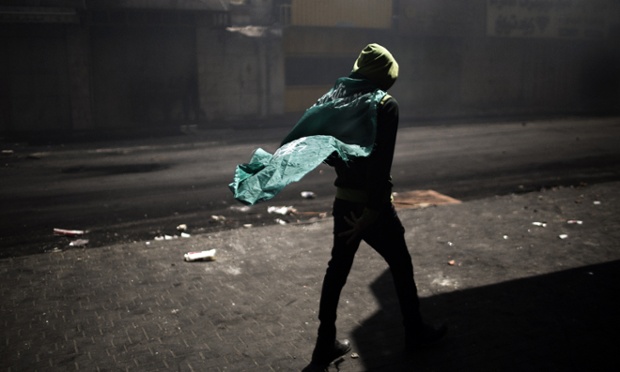 A Palestinian demonstrator wears a Hamas flag during clashes with the Israeli army in Hebron. Palestinians across the West Bank and Gaza were observing a general strike, with prisoners refusing food to mourn the death of a fellow inmate in an Israeli jail.