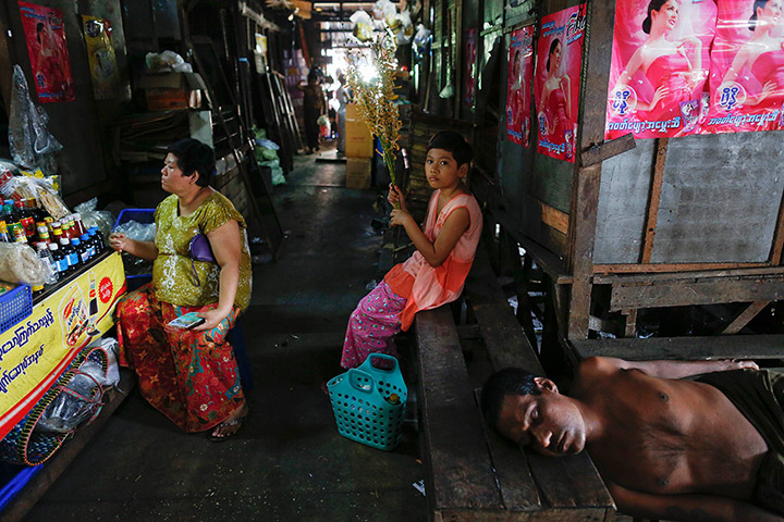 24 hours: Rangoon, Burma: A man sleeps while people shop at a market in the central, 