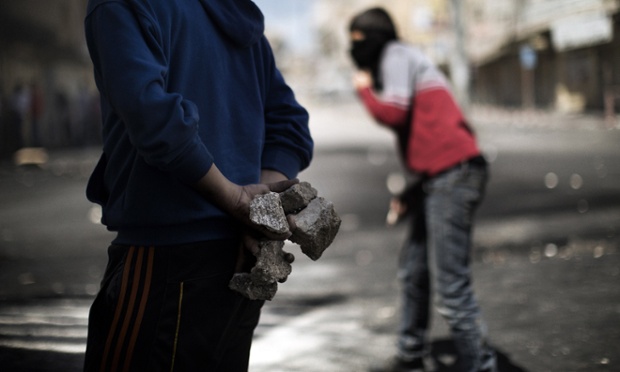 A Palestinian demonstrator prepares to throw rocks.