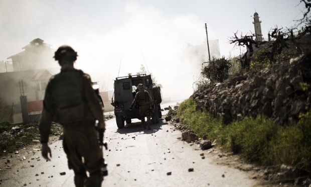 Israeli soldiers walk toward a cloud of tear gas during clashes with Palestinian stone throwers at the al-Arub refugee camp North of the West Bank city of Hebron.