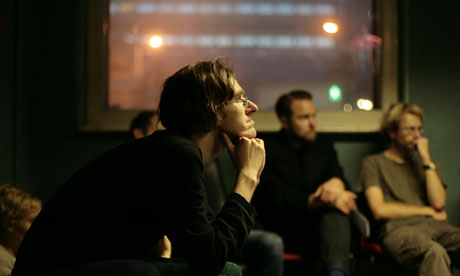 Man rests head on hands as he listens to speaker