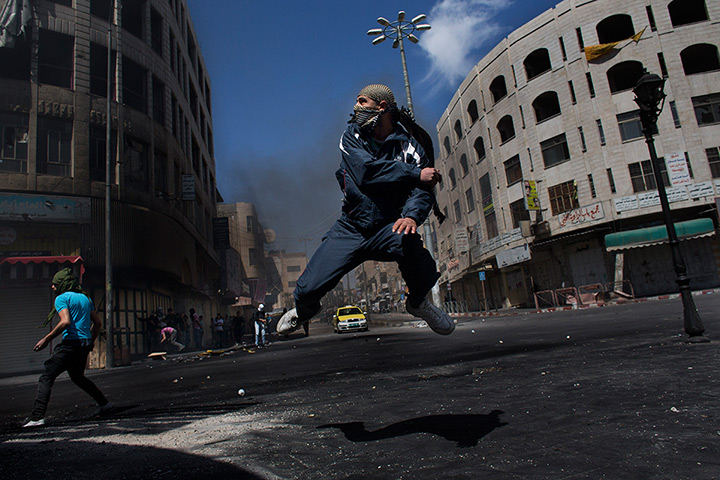 24 hours in pictures: A Palestinian throws a stone towards Israeli forces