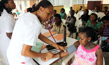 A nurse checks a pregnant woman's blood pressure at a maternity hospital in Nigeria.