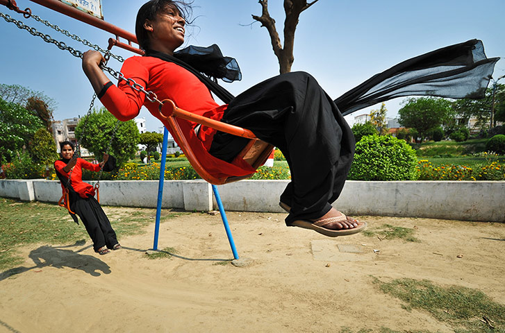 Members of the Red Brigade play on swings 