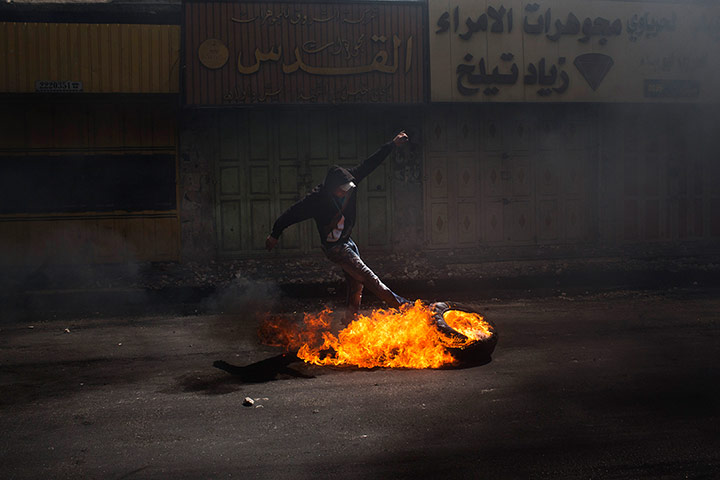 20 Photos: A Palestinian protester kicks a burning tyre in Hebron
