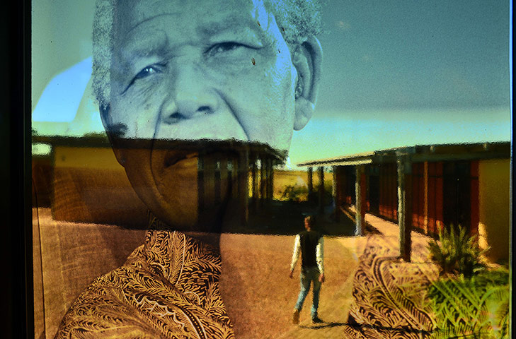 24 Hours: A man in front of a transparent window bearing the image of Nelson Mandela