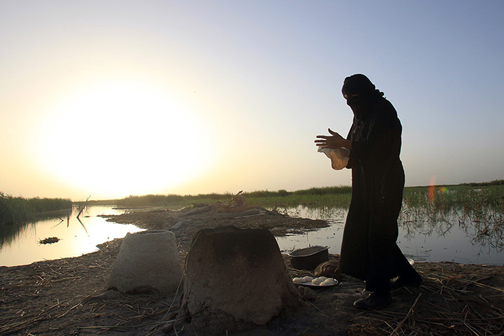 24 hours: Nasiriyah, Iraq: A woman bakes bread in a traditional clay oven 