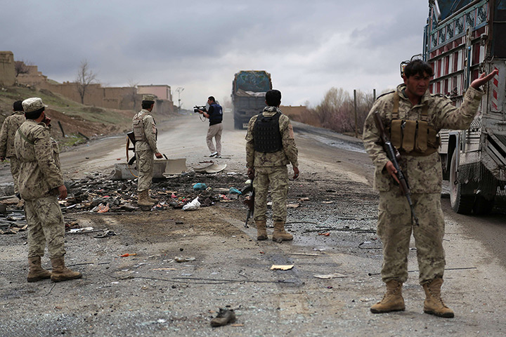 24 hours: Afghanistan: Security forces stand guard at the site of a roadside bomb