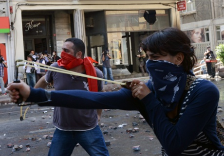 A demonstrator uses a slingshot as clashes erupt between police and protesters during May Day celebrations in Istanbul, Turkey, Wednesday May 1, 2013.