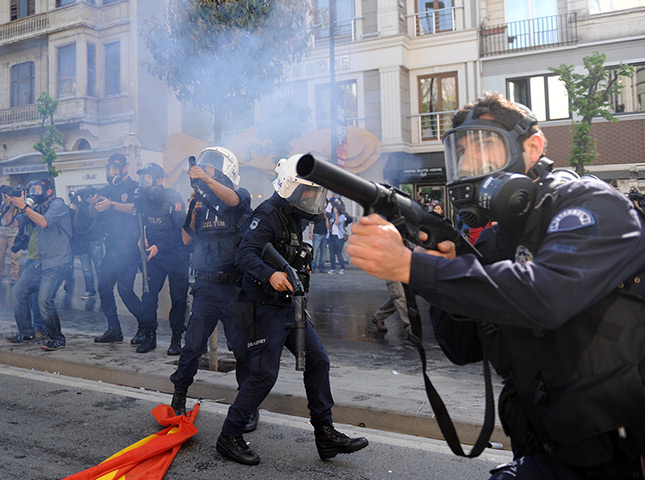 May Day: A masked policeman fires teargas during clashes in Istanbul