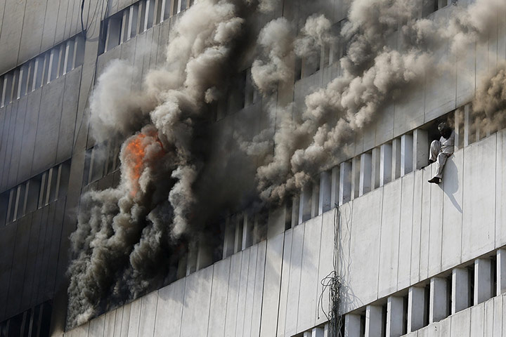 20 Photos: A man sits on the window of a burning building in Lahore