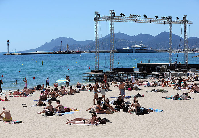 Cannes preparation : Sunbathers on the beach next to the giant Cinema de la Plage screen
