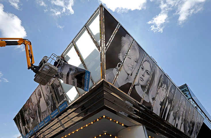 Cannes preperations: Workers install giant posters on the facade of the Casino
