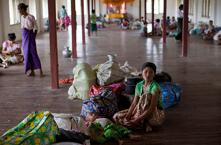 Cyclone Mahasen: A Rakhine Buddhist woman and her child sit with their belongings
