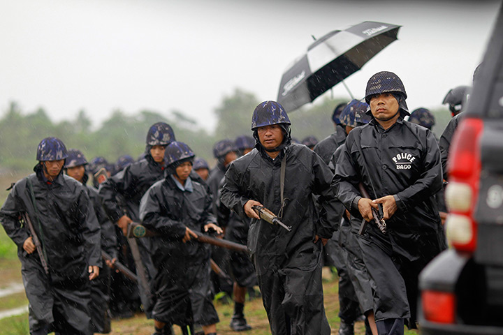 Cyclone Mahasen: Police officers walk in the rain as they guard a camp outside of Sittwe