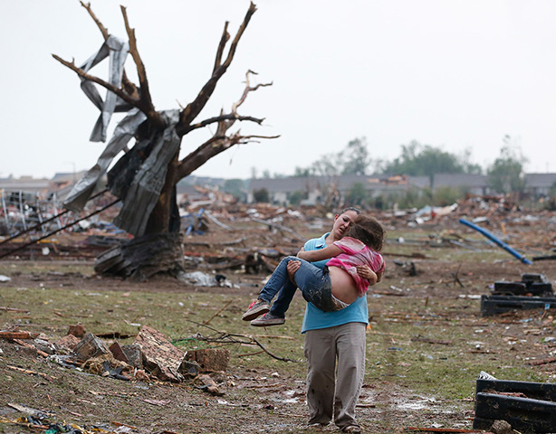 EF-4 update: A woman carries her child through a field near the Plaza Towers Elementary 
