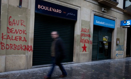 -- A man walks next to the Banco Sabadell, with graffiti: Today all the streets to fight and thieves.