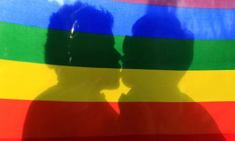 Couple kissing behind rainbow flag