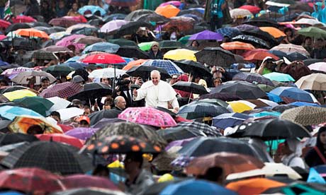 Pope Francis surrounded by Catholics sheltering under umbrellas in St Peter's Square