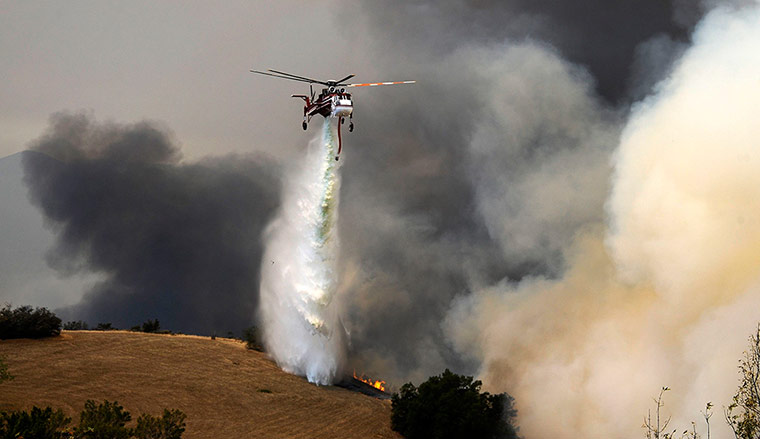 Wildfire: A fire-fighting helicopter drops water