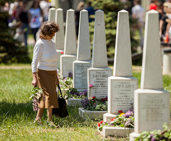 Victory day celebrations: A woman carries flowers to the grave of a fallen relative at the Victory Me