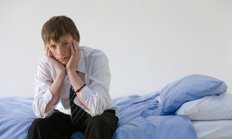 Portrait of a teenage boy sat on a bed