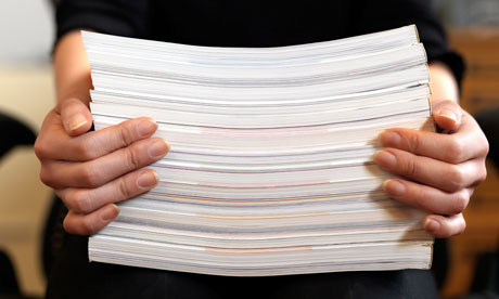 A close up view of female hands holding up a stack of paper while sitting