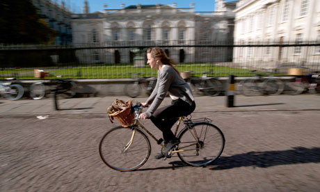 Cambridge University students cycle past the Senate House, Cambridge, England. October 2011