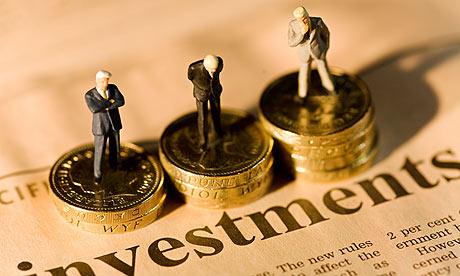 Miniature businessmen standing on stacks of coins on financial newspaper