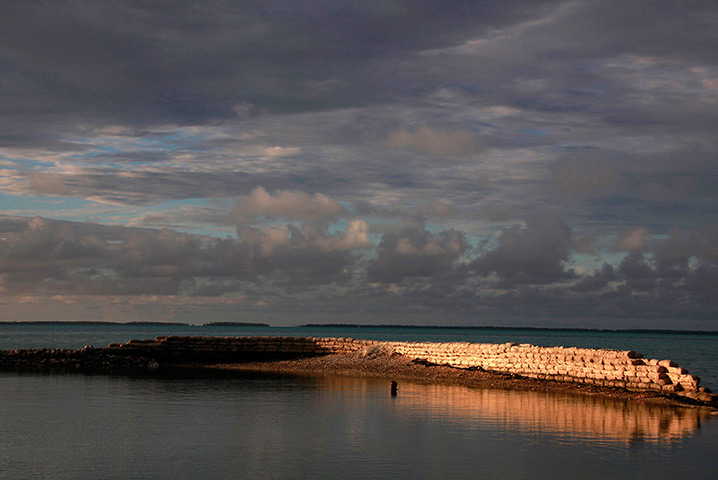 Kiribati, Pacific island: A man swims next to a manmade wall built to protect the island from rising 