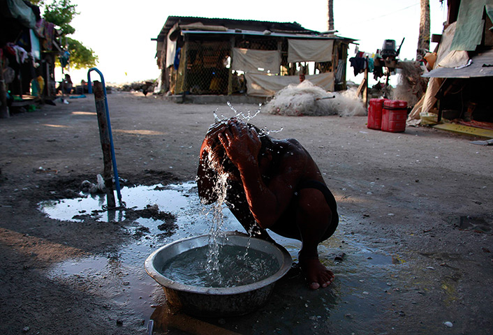 Kiribati, Pacific island: A boy washes himself with water from a well outside his home in the village