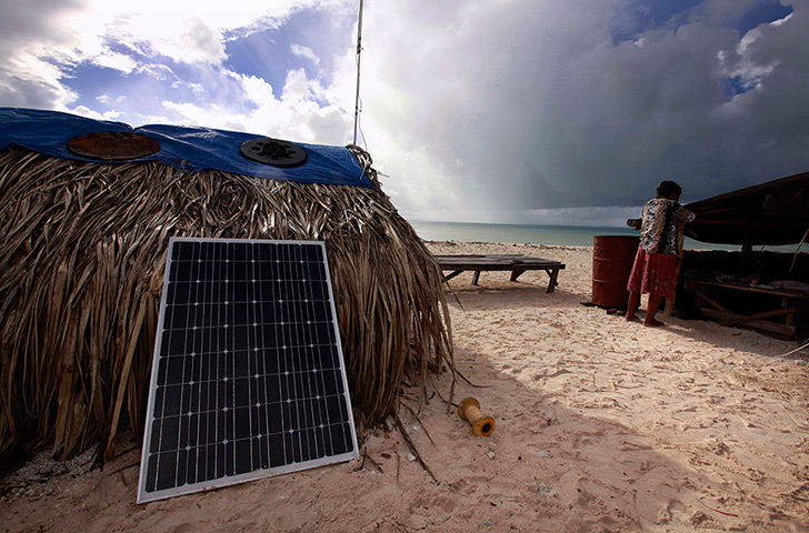 Kiribati, Pacific island: Binata Pinata checks the roof of her home as a storm approaches Bikeman isl