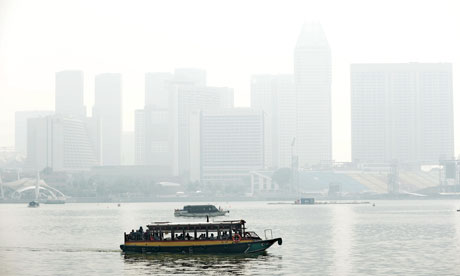 A boat sails along the Marina bay, Singapore, in front of buildings blanketed by haze