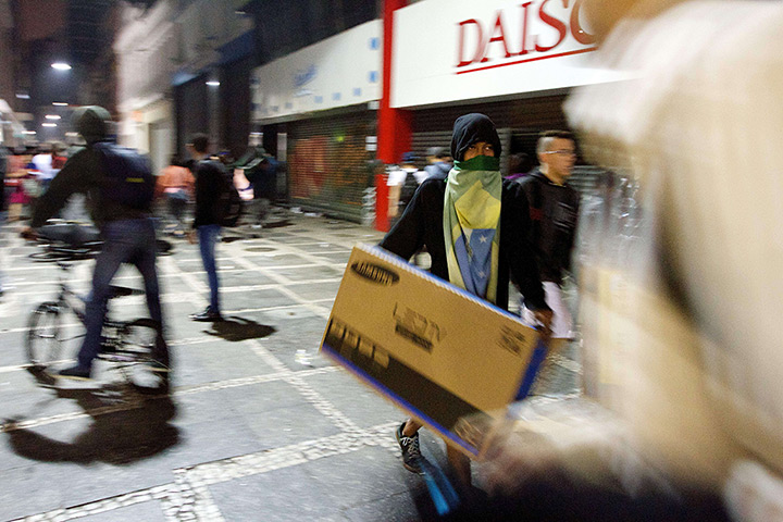 Brazil protests continue: Looters carry a tv sets out damaged shops in Sao Paulo