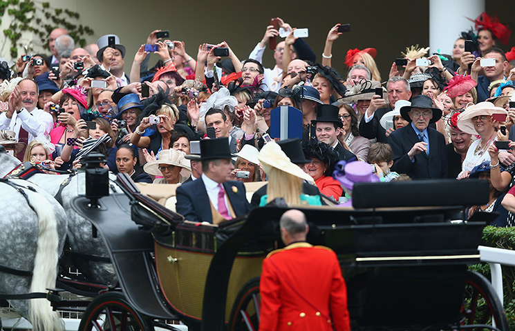 Ladies day at Ascot: Racegoers take photographs as the Royal carriage procession arrives at the 
