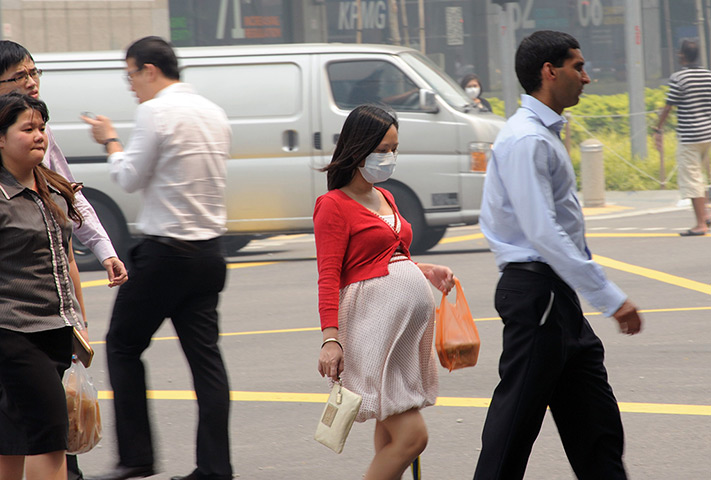 Singapore smog: A pregnant woman with a face mask walking on the street in Singapore