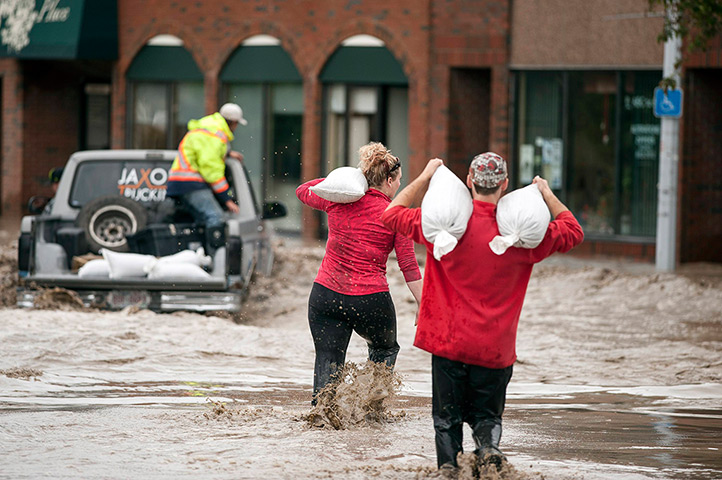 Canada floods: Residents carrying sandbags wade through floodwater in High River in Albert
