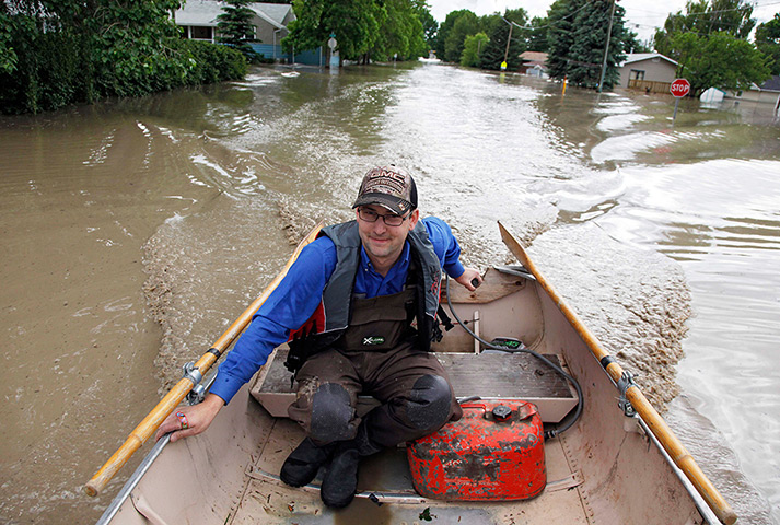 Canada floods: Roger Poirier pilots a boat along a residential street after gathering belo
