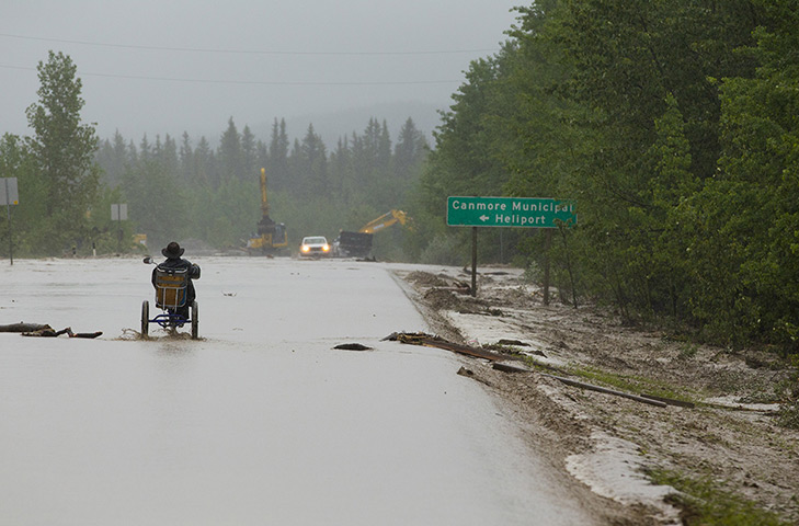Canada floods: A man on a tricycle checks out the Highway 1X after Cougar Creek overflowed