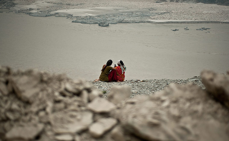 India Food: Local residents sit next to rubble on a damaged road 