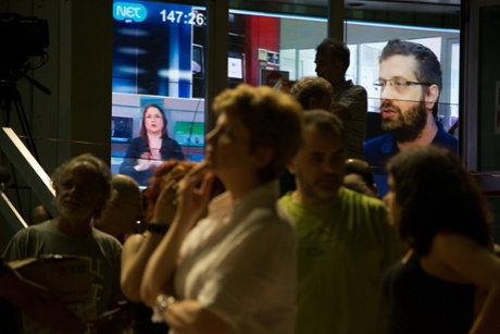 A giant monitor in the courtyard displays an ERT broadcast.