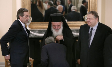 Greece's Prime Minister Antonis Samaras (L) and newly appointed Foreign Minister and Deputy Prime Minister Evangelos Venizelos (R) look at an official kissing the hand of leader of Greek Orthodox church Ieronimos (C) after a swearing in ceremony at the Presidential Palace in Athens June 25, 2013.