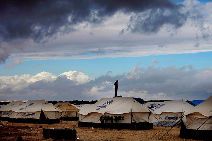 Syrian refugees: A man stands on top of a water tank at Zaatari refugee camp