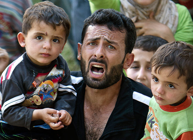 Syrian refugees: A man carrying children shouts during a spontaneous protest 