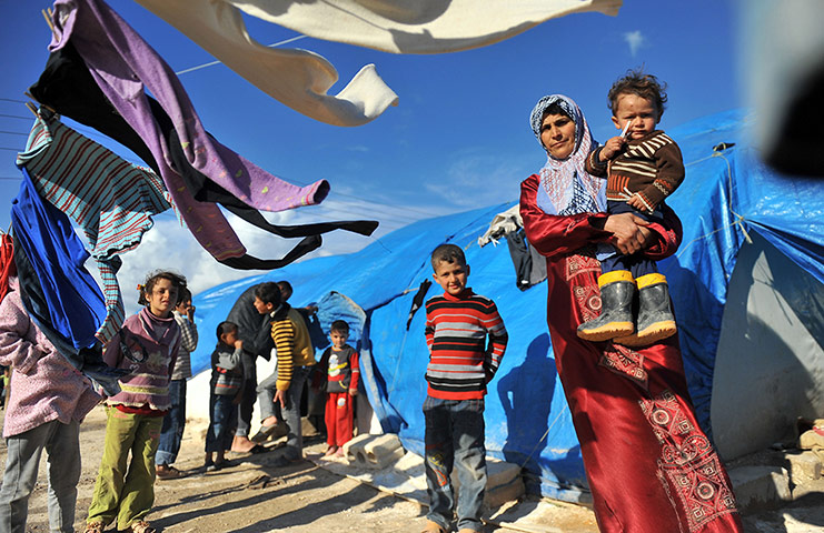 Syrian refugees: A woman carries her child at the refugee camp of Qah