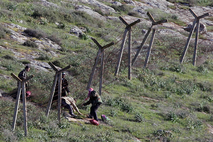 Syrian refugees: A group of men fleeing Syria clear barbed wire to enter Turkey