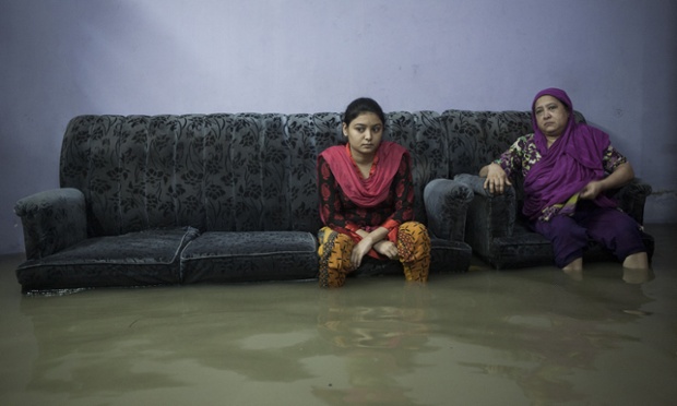 In Bangladesh, a family sit helplessly in the house as it is submerged by flood water.