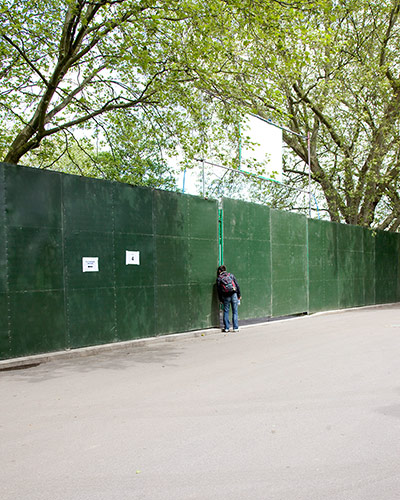 Big Picture - Peeking: person looking through green hoarding