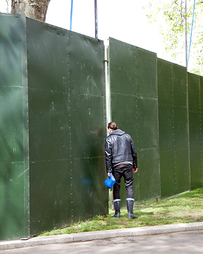Big Picture - Peeking: man looking through gap in green hoarding